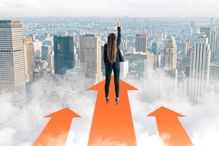 Back view of a young businesswoman with her arm raised, standing on red arrows looking over city buildings, symbolizing the start of a successful trading journey.