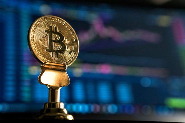 Bitcoin, een belangrijke cryptovaluta-investering voor beginners, afgebeeld als een medaille op een grafiekachtergrond.