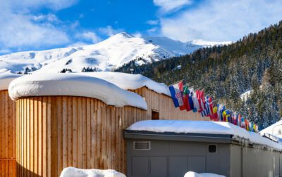 Invloed van Davos op Europese aandelen - , Zwitserland: houten paviljoens met sneeuw en rijen nationale vlaggen voor het World Economic Forum